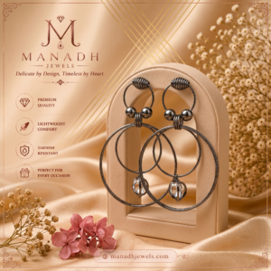 Modern black hoop earrings with sparkling crystal drop accents displayed on a luxurious champagne satin background by MANADH JEWELS.