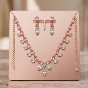 Rose gold plated lightweight jewelry set featuring a necklace and matching drop earrings with pink and clear teardrop stones on a display stand
