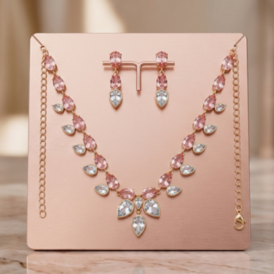 Rose gold plated lightweight jewelry set featuring a necklace and matching drop earrings with pink and clear teardrop stones on a display stand