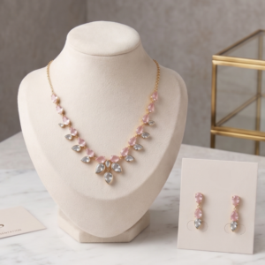 Rose gold plated lightweight jewelry set featuring a necklace and matching drop earrings with pink and clear teardrop stones on a display stand