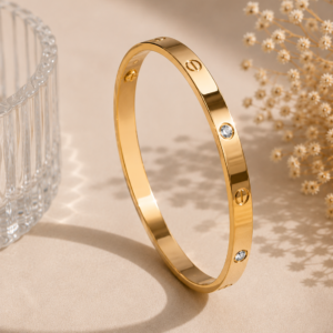 Gold-tone polished bangle with circular detailing and sparkling crystal accents