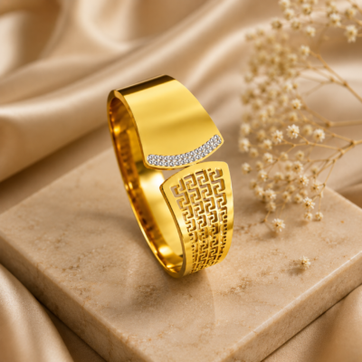 Gold-tone geometric open cuff bangle with patterned detailing and sparkling accent panel