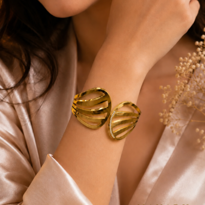 Gold-tone open cuff bangle with flowing layered bands and sparkling crystal accent detailing