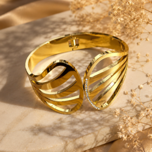 Gold-tone open cuff bangle with flowing layered bands and sparkling crystal accent detailing