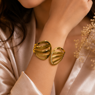 Gold-tone open cuff bangle with flowing layered bands and sparkling crystal accent detailing