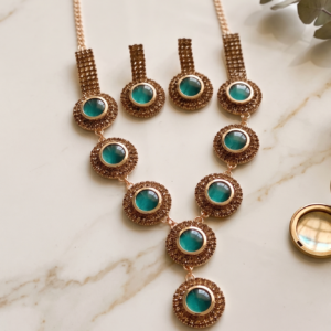 Manadh Jewels gold-plated green stone necklace set with matching earrings displayed on a luxury brown velvet background for festive and bridal jewellery collection