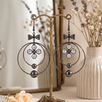 Elegant bow crystal drop earrings by MANADH Jewels featuring a polished metallic circular design with sparkling crystal accents on a premium beige background