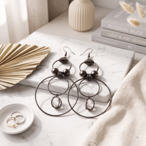 Modern black hoop earrings with sparkling crystal drop accents displayed on a luxurious champagne satin background by MANADH JEWELS.
