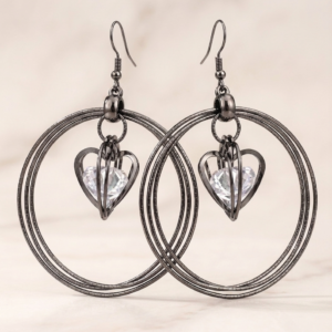 Elegant black hoop earrings featuring sparkling heart-shaped crystal charms displayed on a premium jewellery stand by MANADH JEWELS.