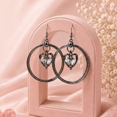 Elegant black hoop earrings featuring sparkling heart-shaped crystal charms displayed on a premium jewellery stand by MANADH JEWELS.