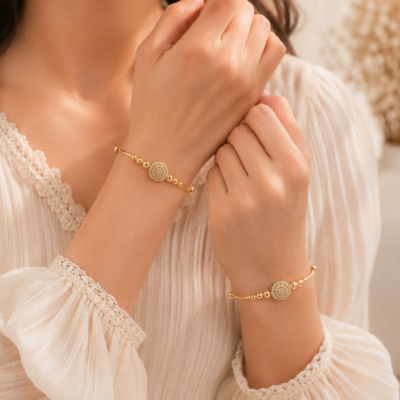 MANADH JEWELS gold bangle bracelet set with intricate diamond-style floral detailing displayed on a luxurious marble stand with elegant golden lighting