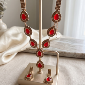 Luxury red stone necklace set with matching earrings by Manadh Jewels displayed on a premium jewelry bust, ideal for bridal, wedding, festive, and party wear