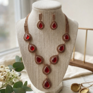 Luxury red stone necklace set with matching earrings by Manadh Jewels displayed on a premium jewelry bust, ideal for bridal, wedding, festive, and party wear