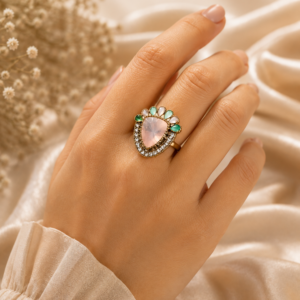 Elegant rose quartz statement cocktail ring featuring a heart-shaped blush pink gemstone with crystal halo and aqua accent stones in a premium gold-tone finish by Manadh Jewels.