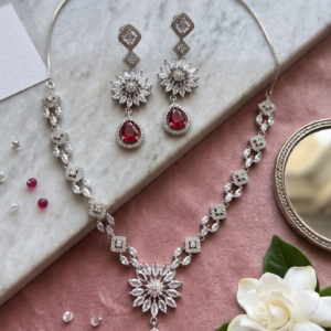 Manadh Jewels Floral Ruby Crystal Necklace Set with matching drop earrings featuring premium crystal floral motifs and ruby-red pear-shaped stones, ideal for bridal wear, weddings, festive celebrations, receptions, and party occasions