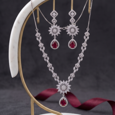 Manadh Jewels Floral Ruby Crystal Necklace Set with matching drop earrings featuring premium crystal floral motifs and ruby-red pear-shaped stones, ideal for bridal wear, weddings, festive celebrations, receptions, and party occasions