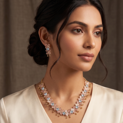 Gold-toned lightweight jewelry set by Manadh Jewels featuring a necklace and matching earrings with pink butterfly motifs and clear American diamond stones