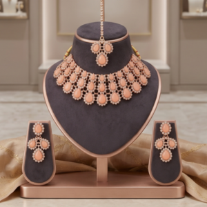 Manadh Jewels luxurious rose gold bridal choker necklace set featuring layered teardrop peach stones and sparkling crystals, complete with matching drop earrings and a coordinating maang tikka