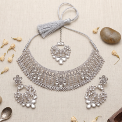 Manadh Jewels silver-tone bridal choker necklace set featuring intricate floral motifs and clear crystal mirror-style stones, complete with matching drop earrings and a coordinating maang tikka