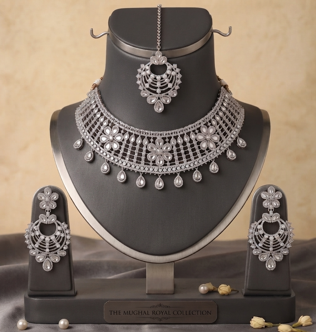 Silver-Toned Floral Bridal Choker Set with Earrings & Tikka Manadh Jewels silver-tone bridal choker necklace set featuring intricate floral motifs and clear crystal mirror-style stones, complete with matching drop earrings and a coordinating maang tikka