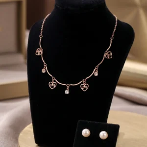 Rose gold-tone necklace with heart charms reading LOVE and YOU alongside pearl stud earrings