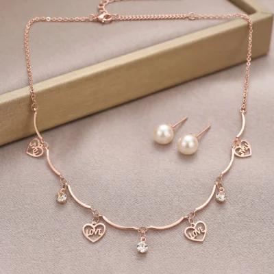Rose gold-tone necklace with heart charms reading LOVE and YOU alongside pearl stud earrings