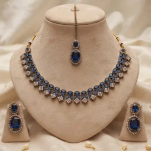 Antique gold-plated traditional Indian choker necklace set featuring deep royal blue stones, accompanied by matching drop earrings and a maang tikka