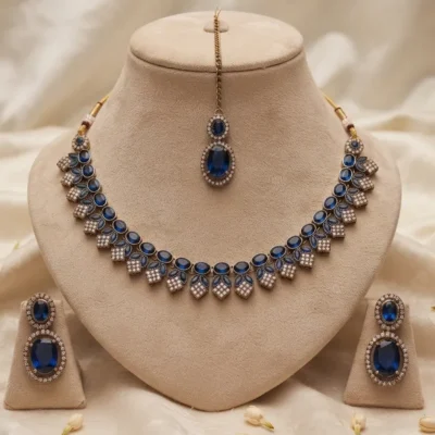 Antique gold-plated traditional Indian choker necklace set featuring deep royal blue stones, accompanied by matching drop earrings and a maang tikka