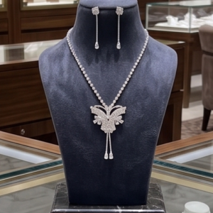 Silver-tone crystal butterfly pendant necklace with matching rhinestone drop earrings held in a hand