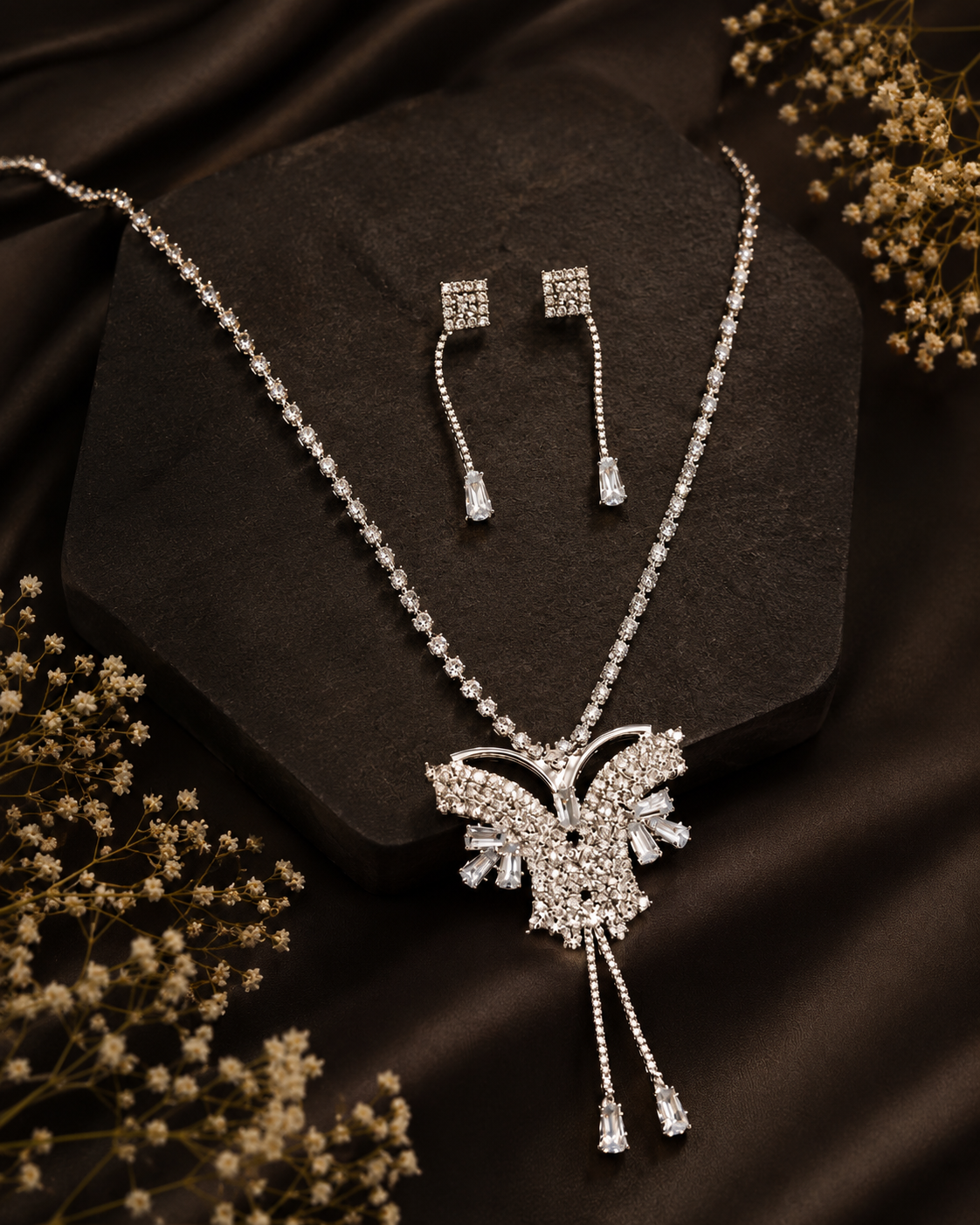 Silver Crystal Butterfly Necklace &_ Earring Set 2 Silver-tone crystal butterfly pendant necklace with matching rhinestone drop earrings held in a hand