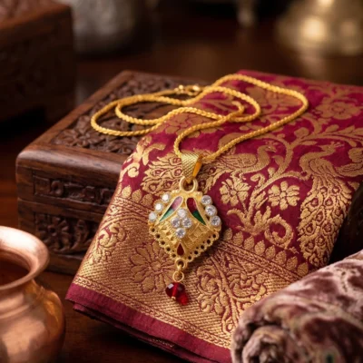 Gold pendant necklace with multicolor details and red bead drop